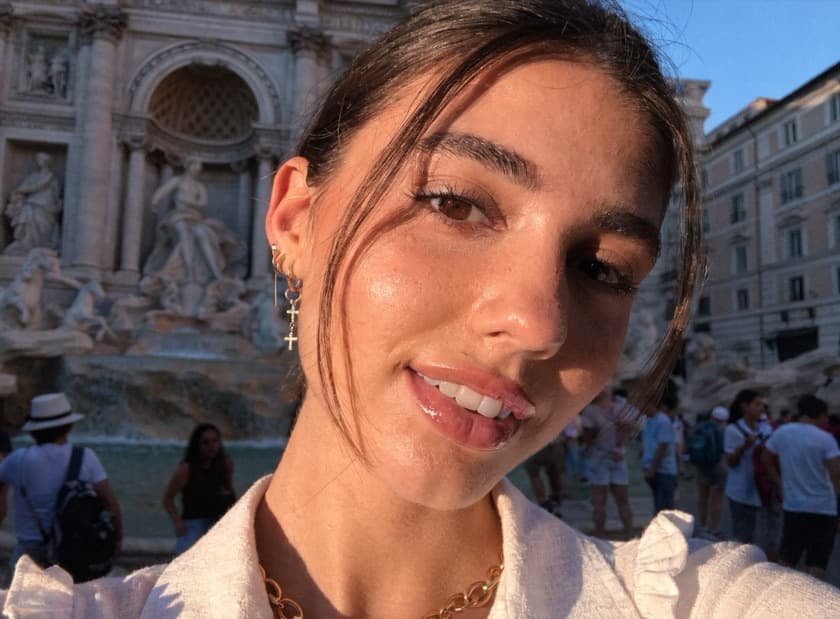 A too-perfect dating-app selfie of a person who does not exist, posed at the Trevi Fountain